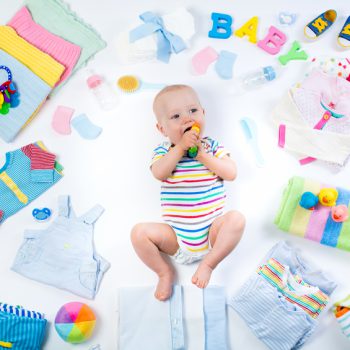 Baby on white background with clothing, toiletries, toys and health care accessories. Wish list or shopping overview for pregnancy and baby shower. View from above. Child feeding, changing and bathing